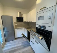 A kitchen with a built-in oven, white cabinets, and a wood-patterned floor in a 2-room apartment.