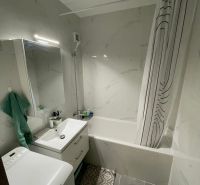 Bathroom in a 2-room apartment with a bathtub, sink, washing machine, and tiles.