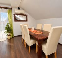 Dining room in a family house with a wooden decor floor and large windows.