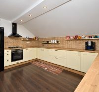 A kitchen in a family house with a wooden decor floor and cream cabinets.