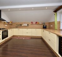 A spacious kitchen in a family house with a wooden decor floor and light furniture.