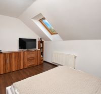 Attic bedroom with wood-patterned flooring in a family house.