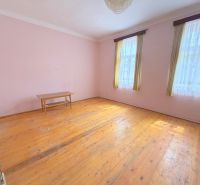 A room in a family house with a wooden decor floor, a table, and curtains.