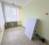 The interior of a family house with a painting, windows with white curtains, and green walls.
