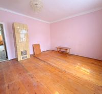 A room in a family house with a tiled stove and a floor with a wooden decor.