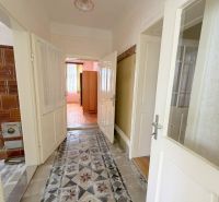 A hallway with a tiled stove and flooring in a family house.