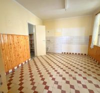 A kitchen in a family house with tiles and wooden wall cladding.