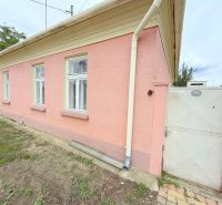 A family house in Dunakiliti with a pink facade, white windows, and a gate.