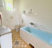 Bathroom with a bathtub and tiles in a family house with simple furnishings.