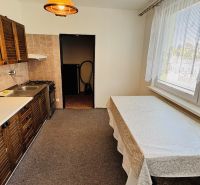 A kitchen in a 3-room apartment with light walls, wooden cabinets, and a dining table.