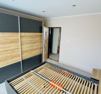 Bedroom with a built-in wardrobe and bed in a 3-room apartment with a wooden decor floor.