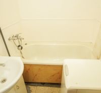 A bathroom in a 2-room apartment with a bathtub, sink, and washing machine.