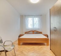 Bedroom in a 2-room apartment with a double bed, chair, and wooden decor flooring.