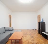 Living room with a gray sofa and a floor with a wooden decor in a 2-room apartment.