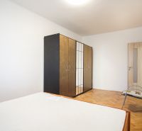 A bedroom with a wardrobe, a bed, and a floor with a wooden decor in a 2-room apartment.