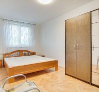 A bedroom in a 2-room apartment with a wood-patterned floor, a bed, and a wardrobe.