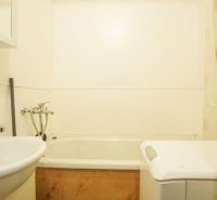 A bathroom in a two-room apartment with a sink, bathtub, and washing machine.