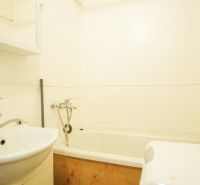 A bathroom with a bathtub and a sink in a 2-room apartment.