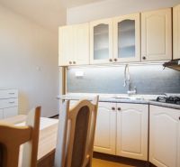 A kitchen unit in a 2-room apartment with a wood decor and a built-in oven.