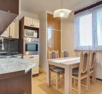Kitchen of a 2-room apartment with a dining table, kitchen unit, and a large window.