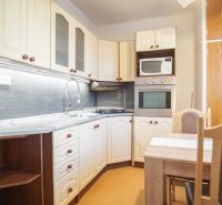 A kitchen in a 2-room apartment with white cabinets and a dining table.