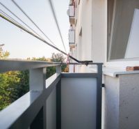 The balcony of a 2-room apartment in Nové Zámky with a view of green trees.