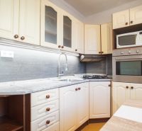 A kitchen in a 2-room apartment with white cabinets and built-in appliances.