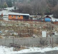 A snowy plot with a family house in Oščadnica surrounded by greenery and wooden structures.