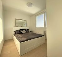 A bedroom with a large bed, a mirror, and windows in a 3-room apartment.