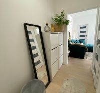 A hallway with white furniture, a mirror, and decorative items in a 3-room apartment.