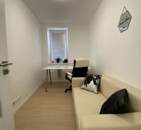 A narrow work corner in a 3-room apartment with a desk, chair, and sofa.
