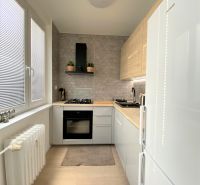 A kitchen in a 3-room apartment with white cabinets, a gas stove, and a radiator.