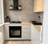 Compact kitchen in a 3-room apartment with a stove, sink, and gray brick tiles.