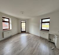 A room with windows, white walls, a wood-patterned floor, and a sink in the office.