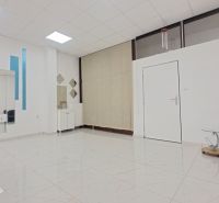 Interior of commercial spaces with a chair, mirrors, and tiles with a white pattern.