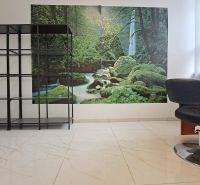 Interior of commercial premises with a shelf, chair, and natural motif on the wall.
