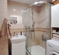 Bathroom with a sink, shower, and washing machine in a 3-room apartment, beige tiles.