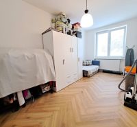 A room in a 3-room apartment with a wooden decor floor, a wardrobe, and a vacuum cleaner.