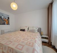 A bedroom with a light bed and nightstands in a three-room apartment with wall decorations.