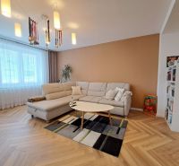 Living room in a 3-room apartment with a white sofa and a floor with a wood decor.