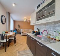 A kitchen with a dining area in a 3-room apartment, a floor with a wood decor, a sofa.