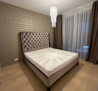 Bedroom in a 2-room apartment with a bed, curtains, and a wooden decor floor.