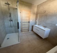 A bathroom in a family house with a double sink and a shower, decorated with light tiles.