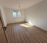 A room in a family house with a wooden decor floor and a large window.