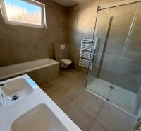 A bathroom in a family house with a bathtub, a shower, and two sinks.