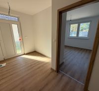 Hallway with wood-patterned flooring in a family house, next to a room with windows.