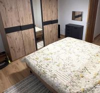 Bedroom with a bed, wardrobe, and wooden decor flooring in a family house.