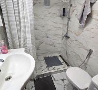 A bathroom in a family house with a sink, shower, and tiles with a marble design.