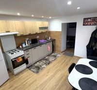 A kitchen in a family house with a wood-patterned floor, a white refrigerator, and a dining table.