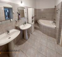 A bathroom with two sinks, a corner bathtub, and light tiles in a 2-room apartment.